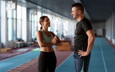 Clientă discutând cu un antrenor personal înainte de o ședință de fitness