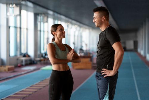Clientă discutând cu un antrenor personal înainte de o ședință de fitness