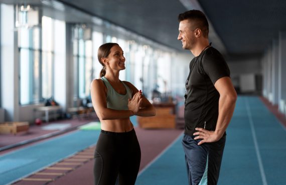 Clientă discutând cu un antrenor personal înainte de o ședință de fitness